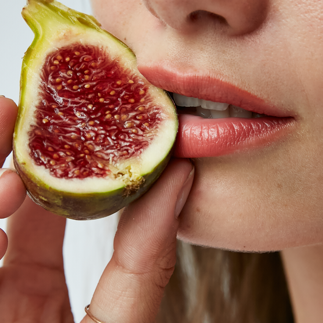 Person about to bite into a halved fig