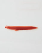 Red ip gloss swatch on a white background