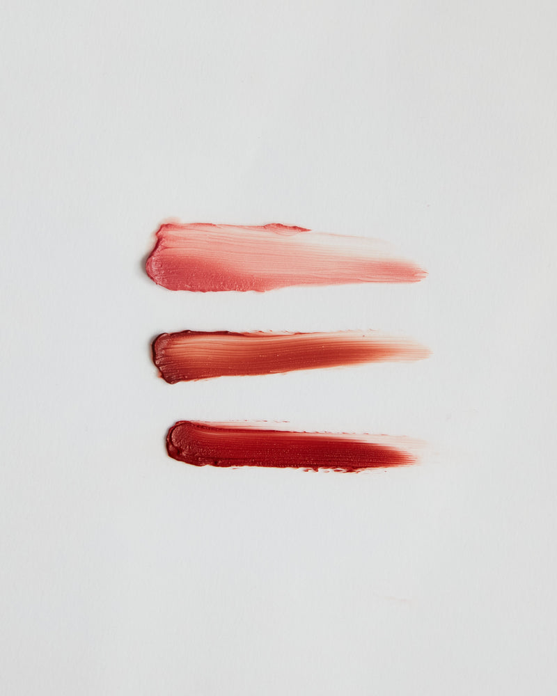 Three swatches of different lip gloss shades on white background