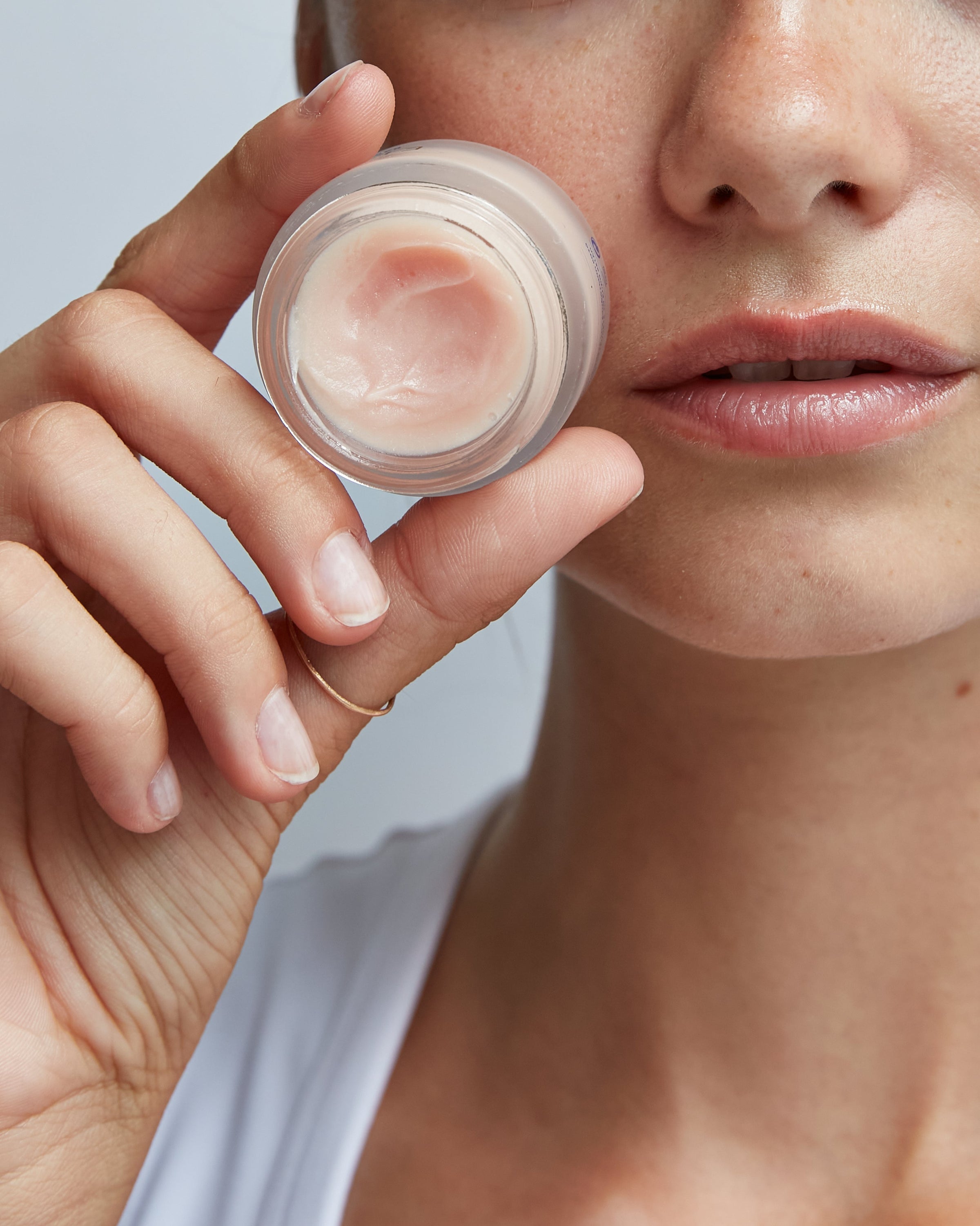 Person holding a small container of lip mask close to their face