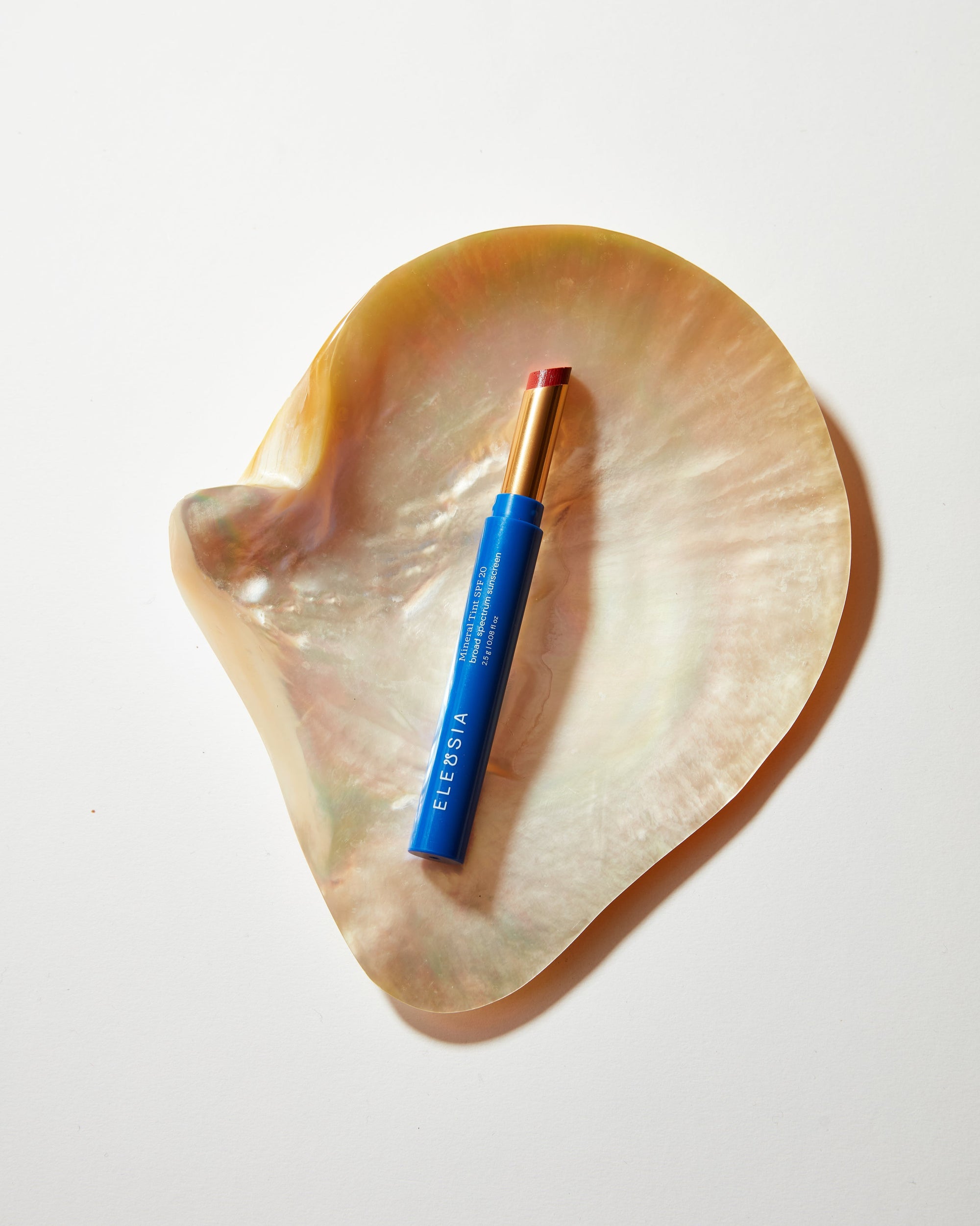 Blue lip tint on a heart-shaped shell with a white background