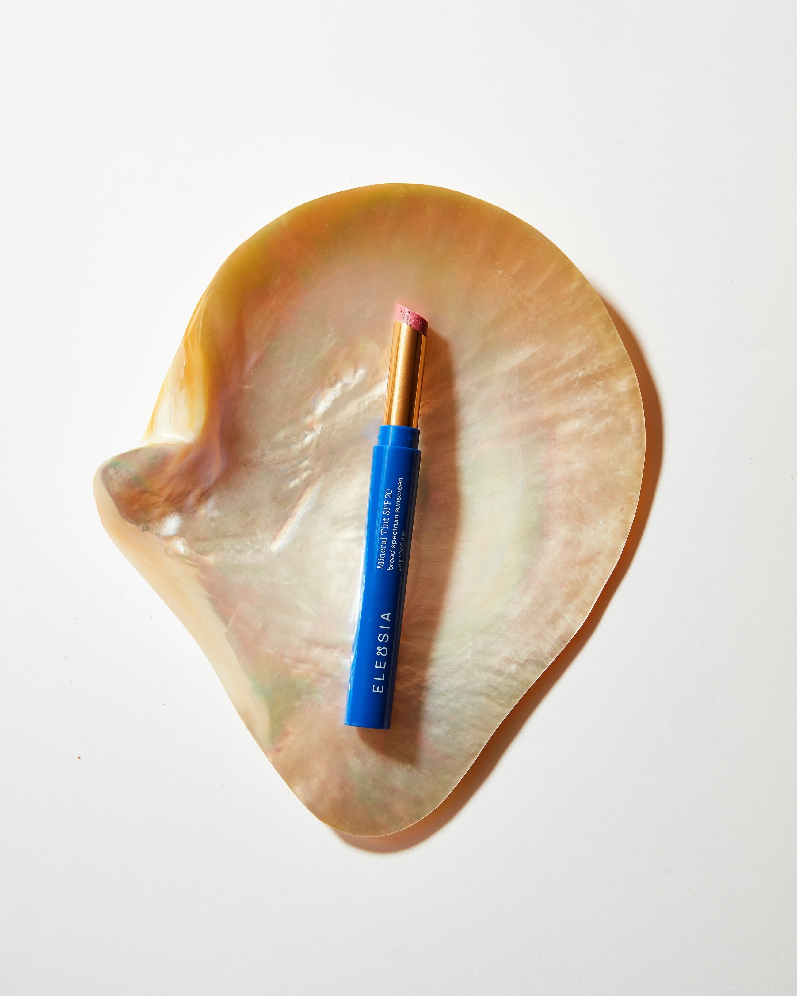 Blue Eleusia lip tint on a large shell with a white background