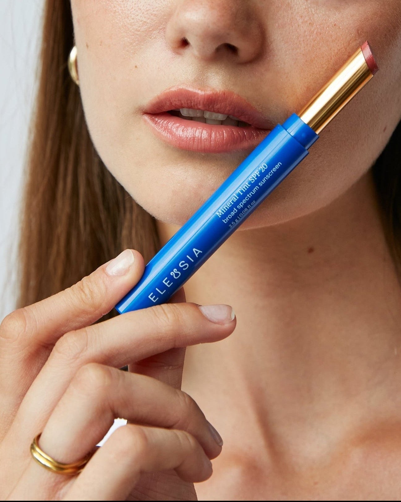 Woman holding a blue Eleusia lip tint with visible branding